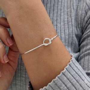 
                  
                    Sterling silver love knot bangle — slim polished friendship bracelet with pressure clasp
                  
                