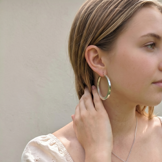 
                    
                      Woman wearing large sterling silver hoop earrings.
                    
                  