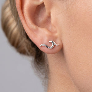 
                  
                    A close-up of a person's ear wearing a small silver wave-shaped stud earring.
                  
                
