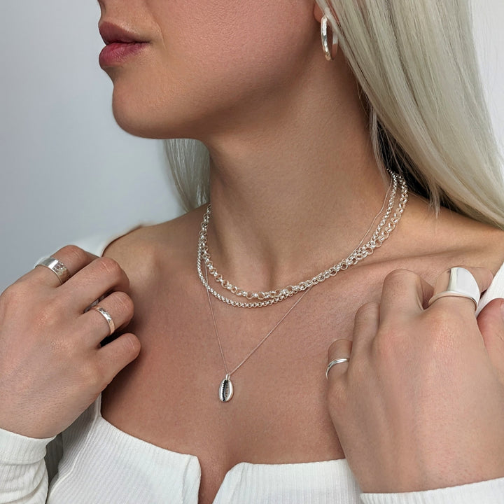 Sterling silver diamond cut hoops styled with faceted rings, chunky rolo chain chokers and cowrie shell necklace