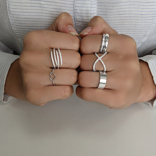 
                    
                      Sterling silver ring stack — multi-row pavé ring and heart ring on one hand, hammered band, crossover pavé ring and chunky band on the other
                    
                  