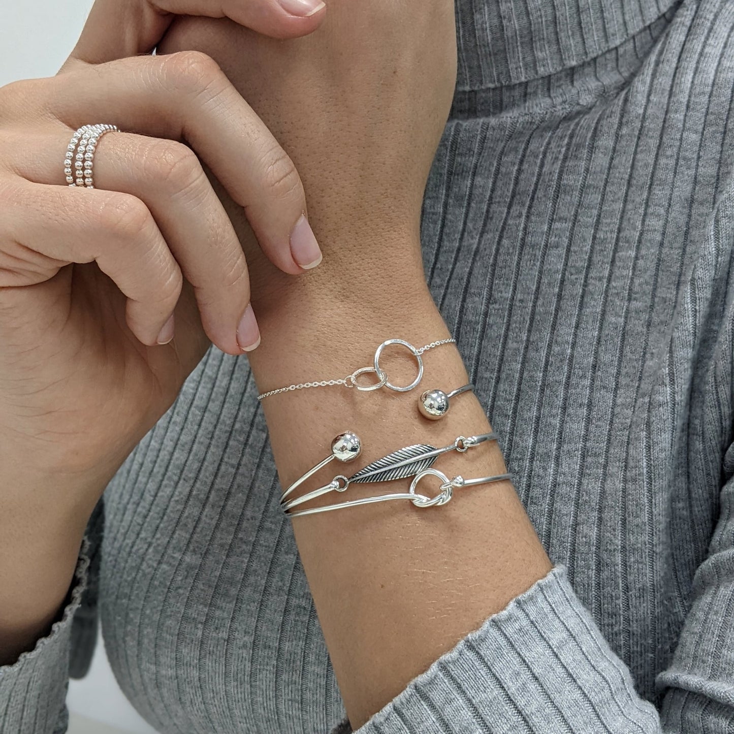 Sterling silver friendship knot bangle styled with a torque bangle and a double circle bracelet