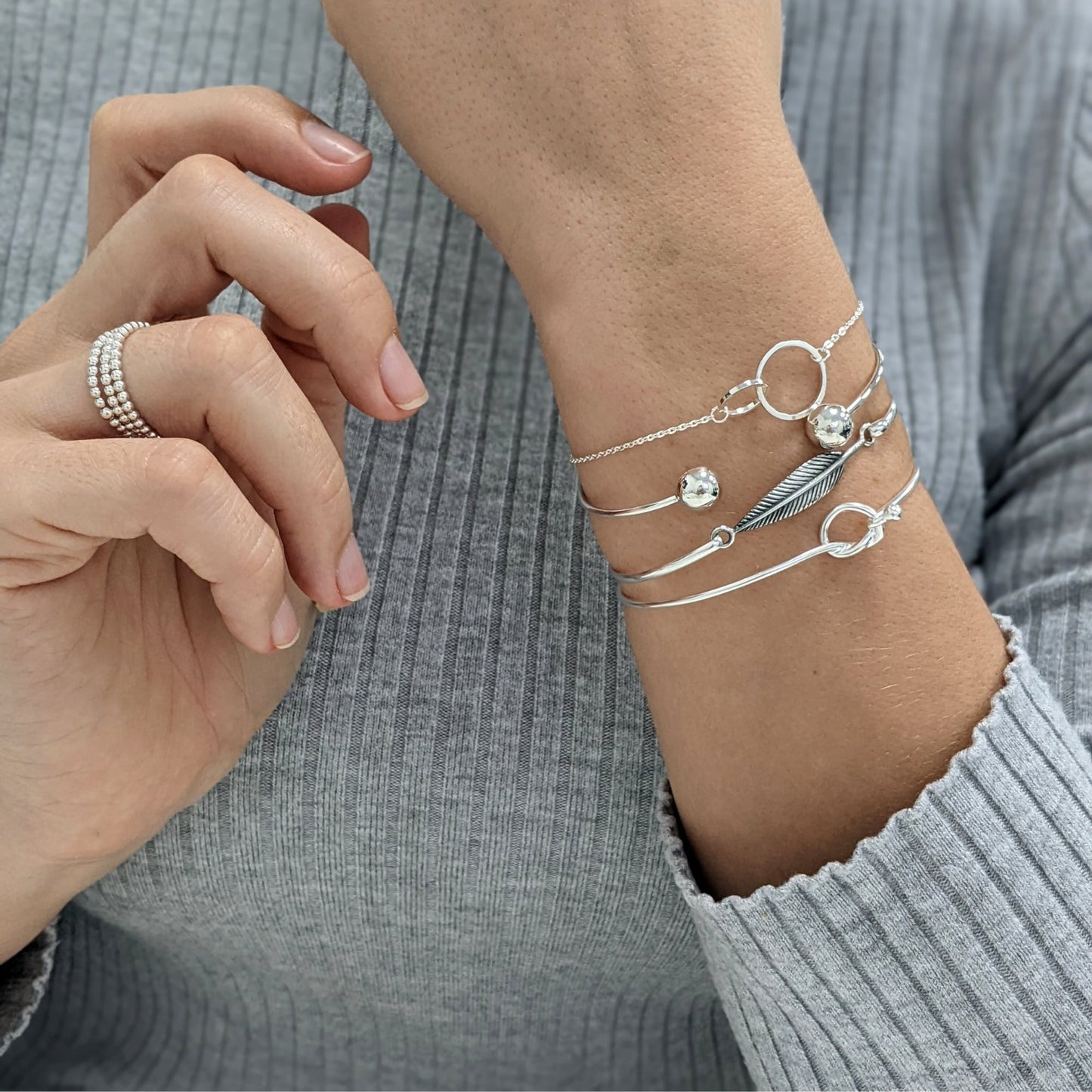 Sterling silver friendship knot bracelet styled with feather and torque bangles