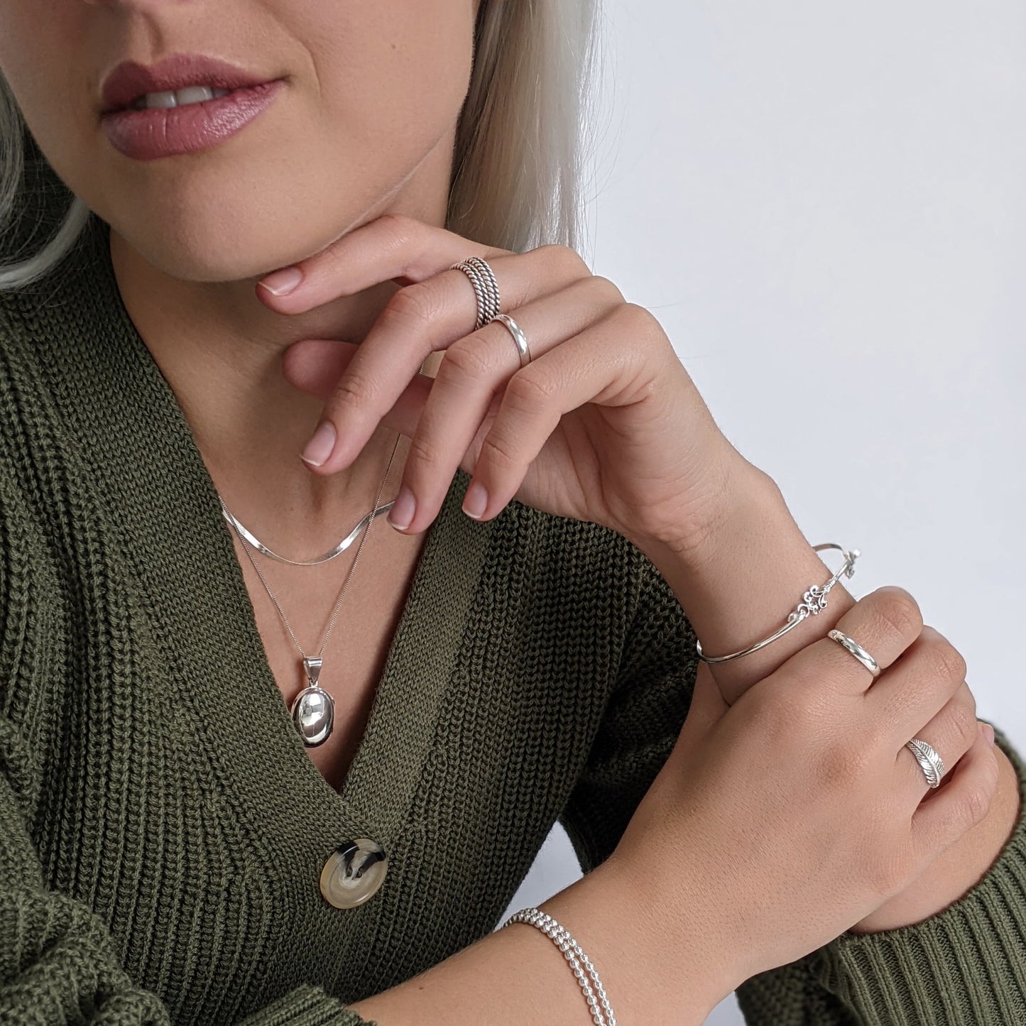Sterling silver court ring styled with oval locket necklace, vintage key bangle and stacking rings