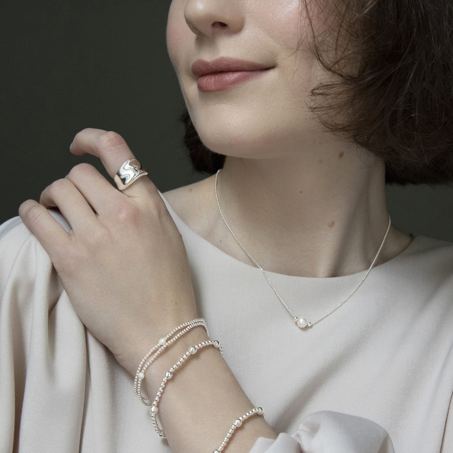 Sterling silver concave ring styled with ball bead bracelets and a pearl necklace