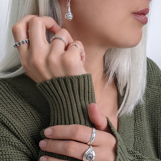 
                    
                      Sterling silver eye ring styled with a skull band ring and filigree teardrop earrings — gothic alternative look
                    
                  