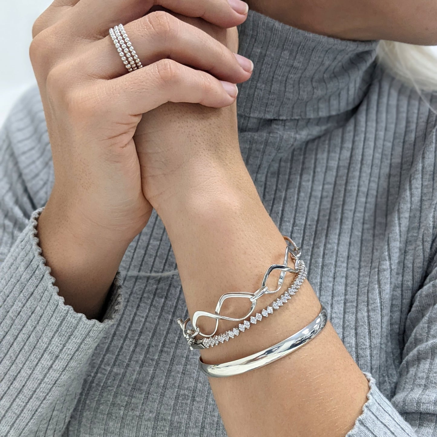 Stacked beaded rings, infinity link bracelet, CZ tennis bracelet, and D-shape bangle