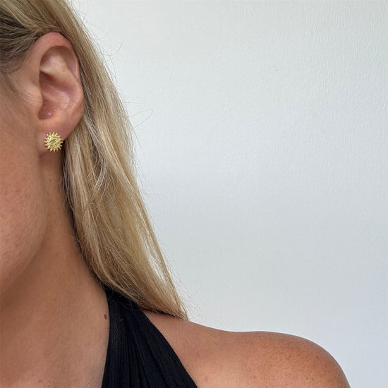 
                    
                      Gold-plated sun and moon stud earrings styled on ear — celestial mismatched design
                    
                  