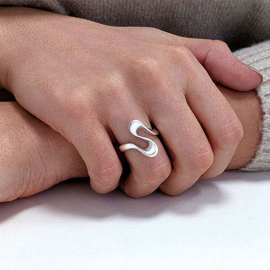 Close-up of sterling silver wavy ring — fluid abstract wave band