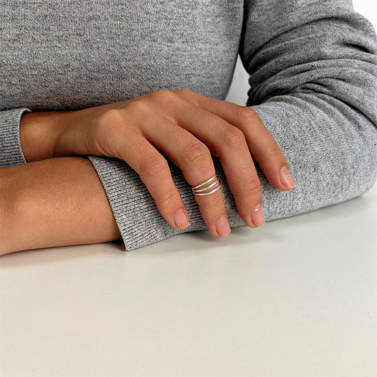 
                    
                      Sterling silver triple band midi ring worn on the upper finger of a woman's hand.
                    
                  