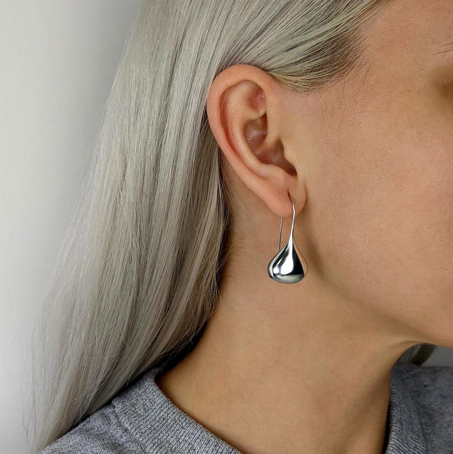Sterling silver puffy teardrop earring worn on ear, hook style