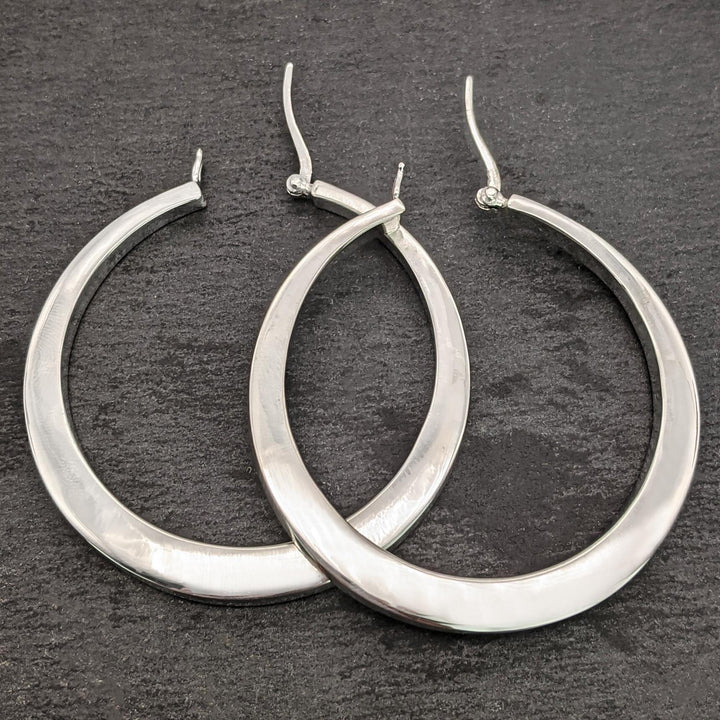 Close-up of large chunky 925 silver hoop earrings with a polished finish