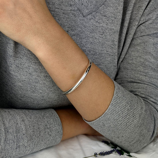 
                    
                      Model wearing a slim sterling silver D-shaped bangle on her wrist
                    
                  