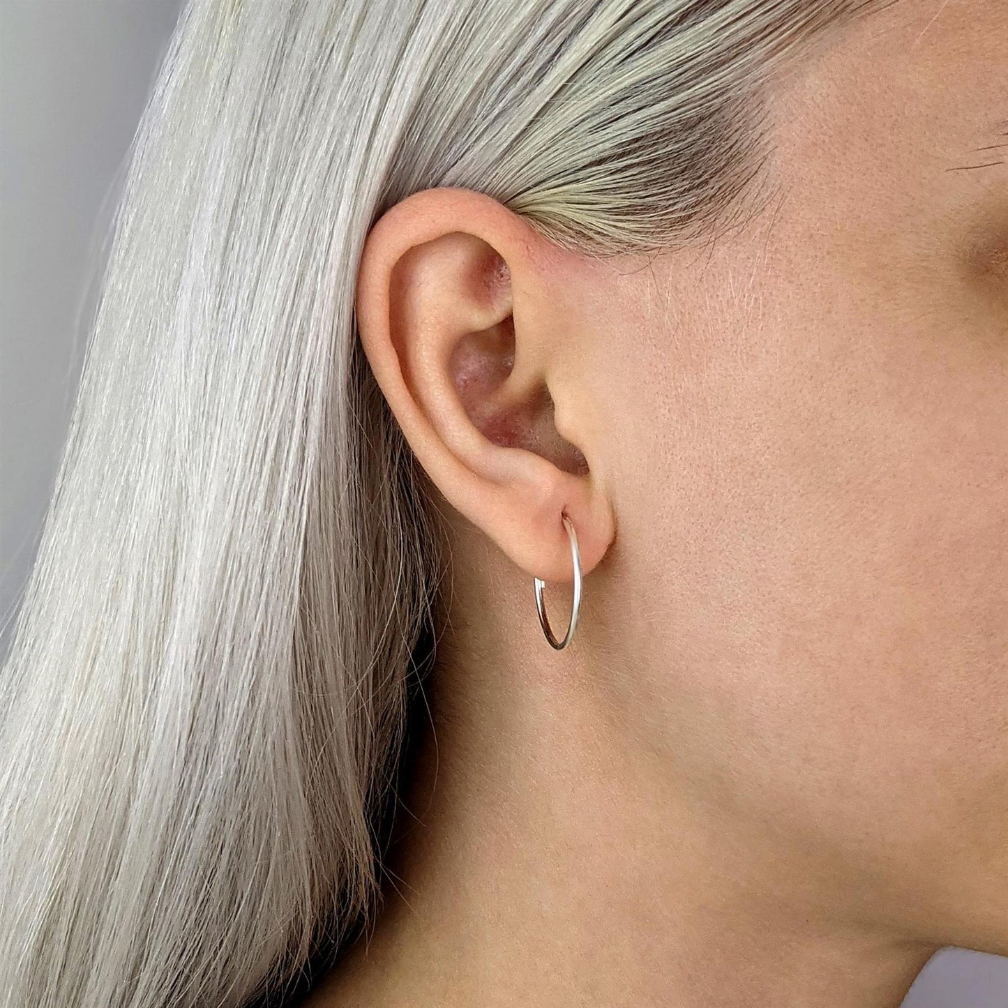 Close-up of sterling silver sleeper earrings — 20mm thin hoops, lightweight design for everyday wear