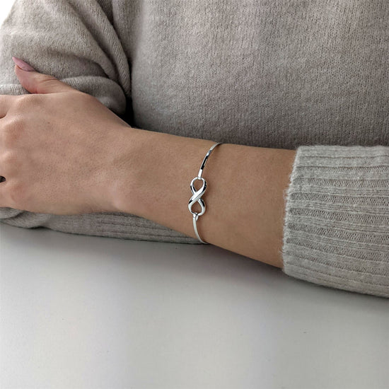 
                    
                      925 sterling silver infinity symbol bangle worn on the wrist, featuring a polished figure-of-eight infinity charm on a slim bangle band
                    
                  