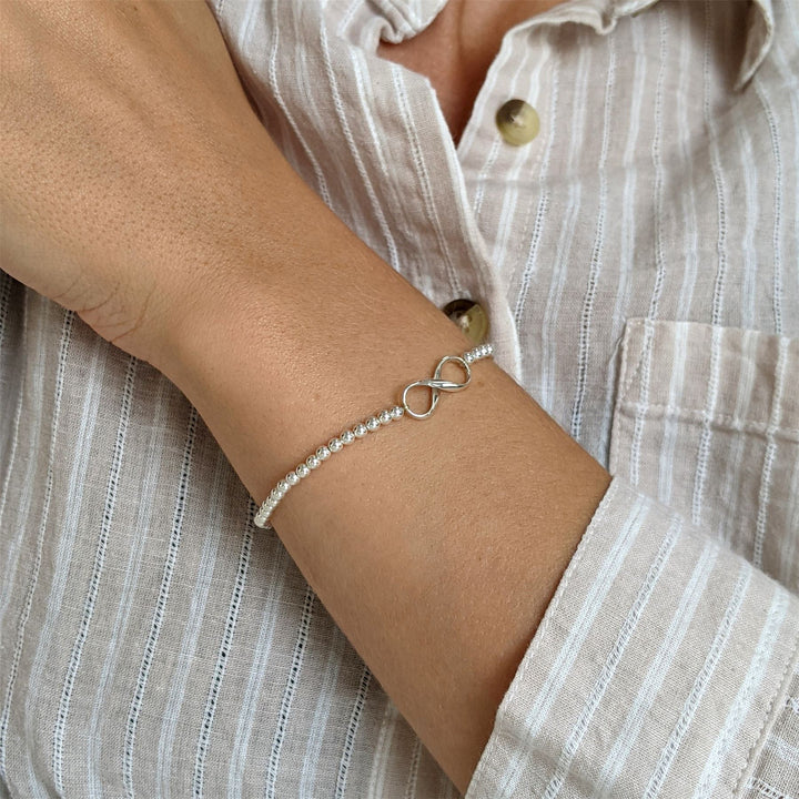 Close-up of sterling silver infinity charm on ball bead stretch bracelet