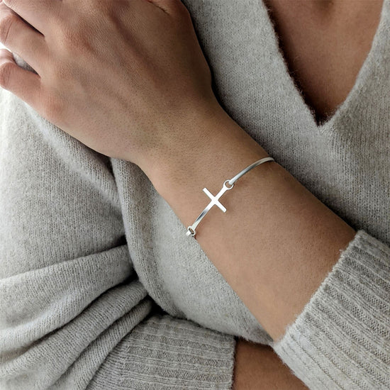 
                    
                      Woman wearing sterling silver bangle with classic cross motif
                    
                  