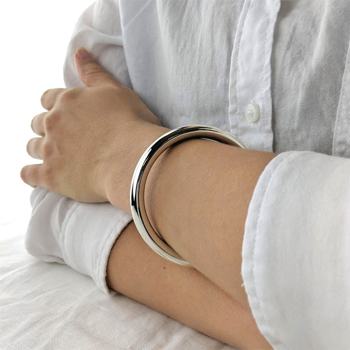 Close-up of chunky 925 silver bangle — smooth polished round tube design
