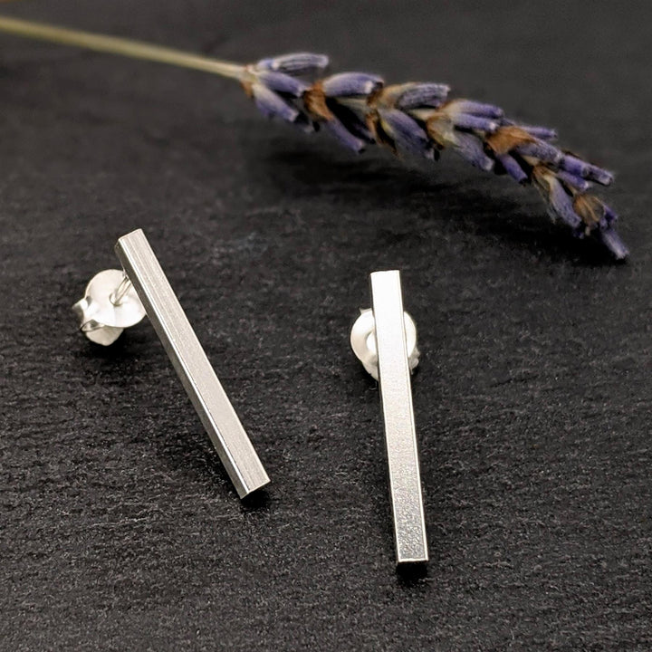 Close-up of sterling silver rectangle bar stud earrings with butterfly backs