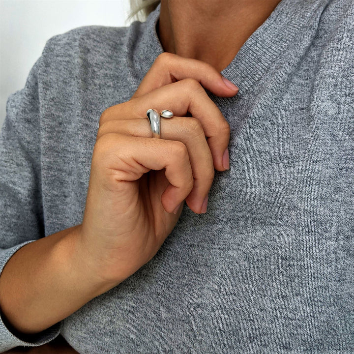 Sterling silver open wrap ring with bulbous ends, worn on finger.