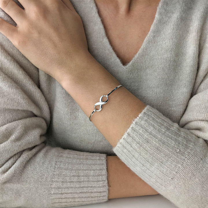Sterling silver thin infinity bangle worn on wrist